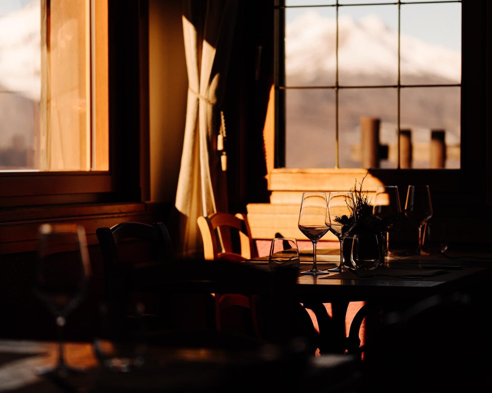 The Yeti dining room at sunset, glasses on the table and the mountains beyond the windows